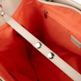 Cartera tipo shopper color taupe, confeccionada en símil cuero texturizado. Tiene doble asa de mano, correa bandolera regulable y herrajes plateados. El acceso es con cierre y cuenta con un compartimento principal con bolsillos internos, uno con cierre y dos abiertos.