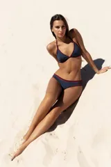 Conjunto de bikini azul con detalles en bordó. El corpiño es triangular fijo con pinza en bajo busto. La bombacha es un culotte con bordes anchos en contraste color bordó.