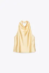 Top color amarillo claro de satén con cuello halter y espalda descubierta. Cierre trasero con botones ocultos.