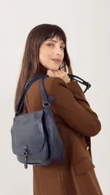 Bandolera color tostado con tapa y broche, bolsillo principal y bolsillos internos organizadores, cierre trasero y correa larga regulable.