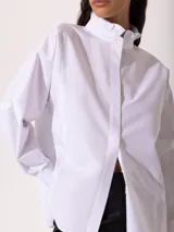 Camisa blanca de corte clásico con detalles en el cuello y mangas largas.