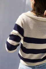 Sweater tejido artesanalmente en hilado 70% algodón y 30% acrílico, con cuello polo y rayas horizontales anchas color azul marino sobre fondo crudo.