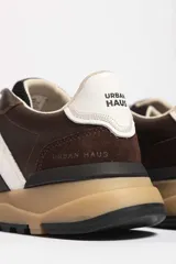 Zapatillas deportivas marrones con detalles en blanco y suela color caramelo.