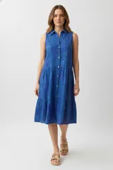 Vestido a la rodilla azul con estampado floral, sin mangas, con cuello camisero y abotonado al frente. Tiene corte holgado y falda con volados.