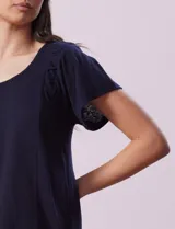 Remera blanca de lino con mangas cortas y fruncido en los hombros.