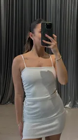 Vestido corto blanco con breteles finos, corte ajustado y frunces laterales.