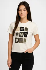 Remera color crema de algodón con estampado de nueve cuadrados con diferentes diseños de corazones en tonos marrones y negros.