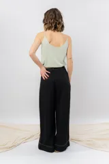 Pantalón negro de corte ancho y fluido, tiro medio con presillas para cinturón, bolsillos laterales funcionales y pinzas delanteras.