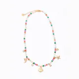 Colgante tipo gargantilla con cadena de eslabones dorados y cuentas facetadas de colores variados (rosa, verde, naranja, celeste, blanco). Incluye dijes colgantes dorados con temática marina: delfín, caracola, estrella de mar, y pequeños cristales redondos engarzados.