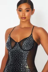 Vestido corto negro ajustado al cuerpo, con breteles finos y escote en V. Presenta detalles de strass plateados en el busto y en todo el frente. Tiene paneles de tul transparente en los laterales.