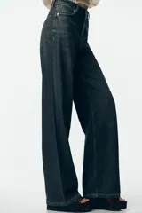 Pantalón de jean de tiro alto color gris oscuro, corte recto, con bolsillos delanteros y traseros. Cierre frontal con cremallera y botón.