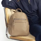 Mochila negra de símil cuero con bolsillo frontal con cierre. En su interior tiene dos bolsillos con cierre y uno abierto con división. Tiene asa de mano y correas regulables.