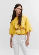 Blusa amarilla corta con cuello redondo, mangas cortas acampanadas y detalle de bordado calado en el ruedo.