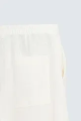 Pantalón de lino color blanco, de corte regular fit. Presenta cintura elástica, bolsillos frontales y traseros de plastrón, con cierre frontal de cremallera y botón.