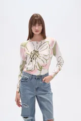 Sweater de tejido de punto, color crema, con estampado floral en tonos rosados y marrones. Presenta cuello redondo y mangas largas.
