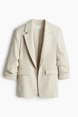 Blazer color crema con solapas de muesca, mangas tres cuartos fruncidas y bolsillos delanteros con solapa. Sin cierre. Forrado.