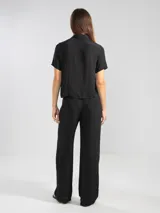 Camisa negra de manga corta en crepé de viscosa suave, con cuello camisero y detalle floral en la botonadura central.