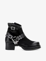 Bota corta de cuero negro, estilo motero, con caña arrugada y suela de plataforma gruesa con envoltura de cuero. Presenta una correa ajustable con hebilla y tachas metálicas alrededor del tobillo.