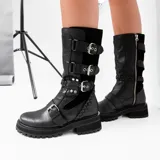 Bota de cuero color marrón con caña media, suela de goma negra, cierre lateral y hebillas ajustables. Presenta detalle trenzado en el talón.