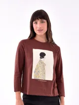 Remera blanca de manga larga con estampa rectangular dorada con diseño animal print y texto 'Fearless, fierce & fabulous'.