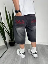 Bermuda de jean gris oscuro con efecto lavado, corte ancho y largo a la rodilla. Bolsillos traseros con bordado de llamas rojas.