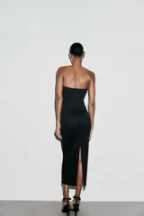 Vestido midi negro entallado, con escote corazón y hombros descubiertos. Cierre lateral con cremallera oculta en costura.