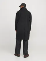 Tapado negro de corte recto, con cuello clásico, cierre frontal con botones ocultos y bolsillos laterales.