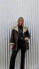 Chaqueta marrón gastado de cuero ovino con cuello y puños de piel sintética color crudo. Cierre frontal con cremallera y bolsillos laterales.