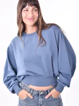 Buzo celeste de corte cropped, con cuello redondo y mangas largas.