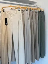 Pantalón de jean celeste de corte ancho con pinzas en la cintura y cinturón plateado con apliques florales.