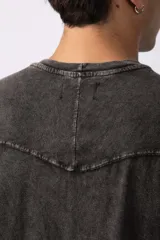 Remera oversize de algodón pesado, color gris oscuro con efecto lavado 'snow' que le da un aspecto gastado y único. Presenta cuello redondo y costuras vistas en hombros y mangas.