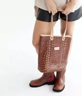 Bolso tipo tote marrón con textura símil cocodrilo, doble asa de hombro color beige y detalle de costuras blancas.