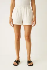 Short blanco de lino con cintura elastizada y apliques bordados en el ruedo.
