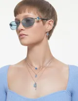 Conjunto de collar y aros Swarovski Iconic Swan, con forma de cisne y cristales color azul hielo. El collar presenta un dije colgante con una piedra en forma de pera.