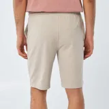 Short deportivo color beige, estilo jogger, con cintura elástica y cordón ajustable.