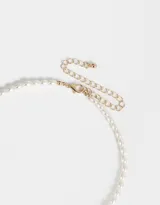 Cadena corta de perlas sintéticas color crema con dije de frutilla rosa y detalles dorados.
