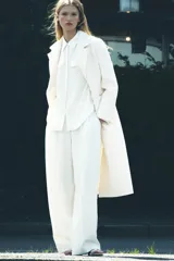 Abrigo largo color crudo de Zara Woman Collection, con cuello solapa, manga larga, bolsillos de vivo con solapa y cierre frontal cruzado con botones.