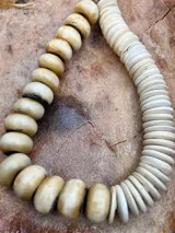 Collar corto de cuentas de hueso en tonos beige y blanco, con cierre de mosquetón dorado.