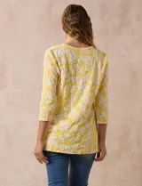 Blusa amarilla con estampado floral blanco, escote en V y mangas 3/4.
