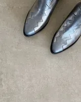 Botín de cuero vacuno color bronce con puntera y caña en cuero negro. Diseño con borde superior en zigzag y taco de madera.