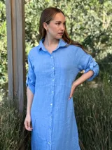 Vestido camisero largo de lino blanco, con corte en la cintura, abertura lateral y botones de nácar.