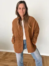 Campera color camel de corte relajado, con exterior de tejido efecto gamuza e interior acolchado. Tiene cuello alto, cierre frontal con cremallera, bolsillos laterales y bolsillo interno.