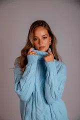 Sweater verde esmeralda de punto trenzado, con cuello alto y mangas largas.
