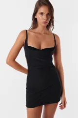 Vestido corto negro de microfibra, ajustado al cuerpo, con breteles elásticos regulables, recortes en el delantero y corpiño inferior de encaje. Espalda descubierta.