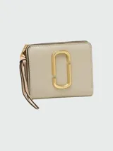 Billetera compacta de cuero color beige con cierre y detalle metálico en el frontal, de la marca Marc Jacobs.