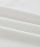 Remera blanca de manga corta con cuello redondo y un pequeño estampado botánico en el lado izquierdo del pecho, que parece ser una ilustración de una planta de café.