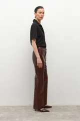 Pantalón de eco cuero color marrón oscuro (chocolate) con textura de cocodrilo (crocco) y corte recto/acampanado.