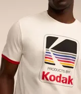 Remera de algodón color crema con cuello redondo y mangas cortas con ribete rojo. Estampa frontal con el logo de Kodak.