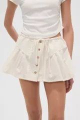 Minifalda plisada color crema con cintura elastizada y cierre frontal con botones de madera.