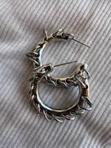 Par de aros plateados tipo argolla con pequeños aros colgando.